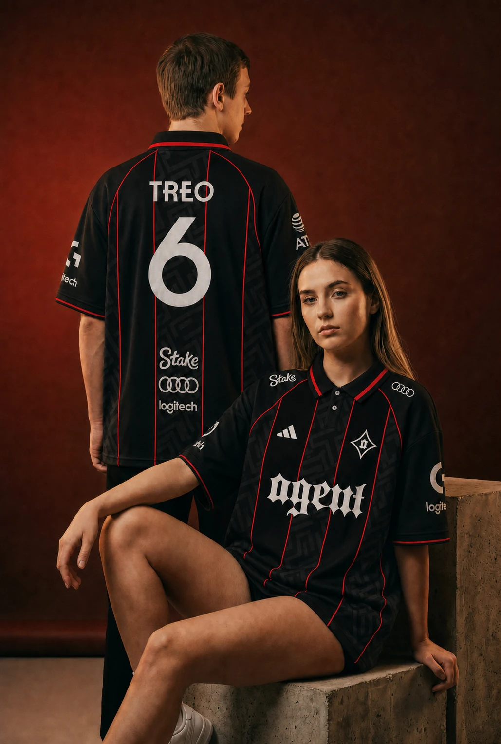 Two models wearing the Agent black kit with red piping in a warm red studio