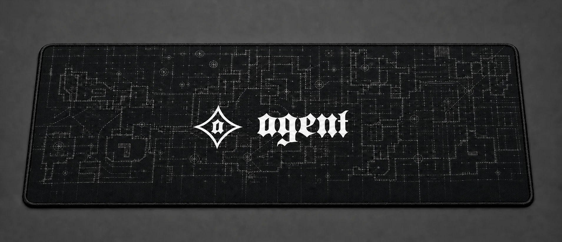 Black extended mousepad with a flat-printed technical blueprint field and centered Agent emblem and wordmark lockup